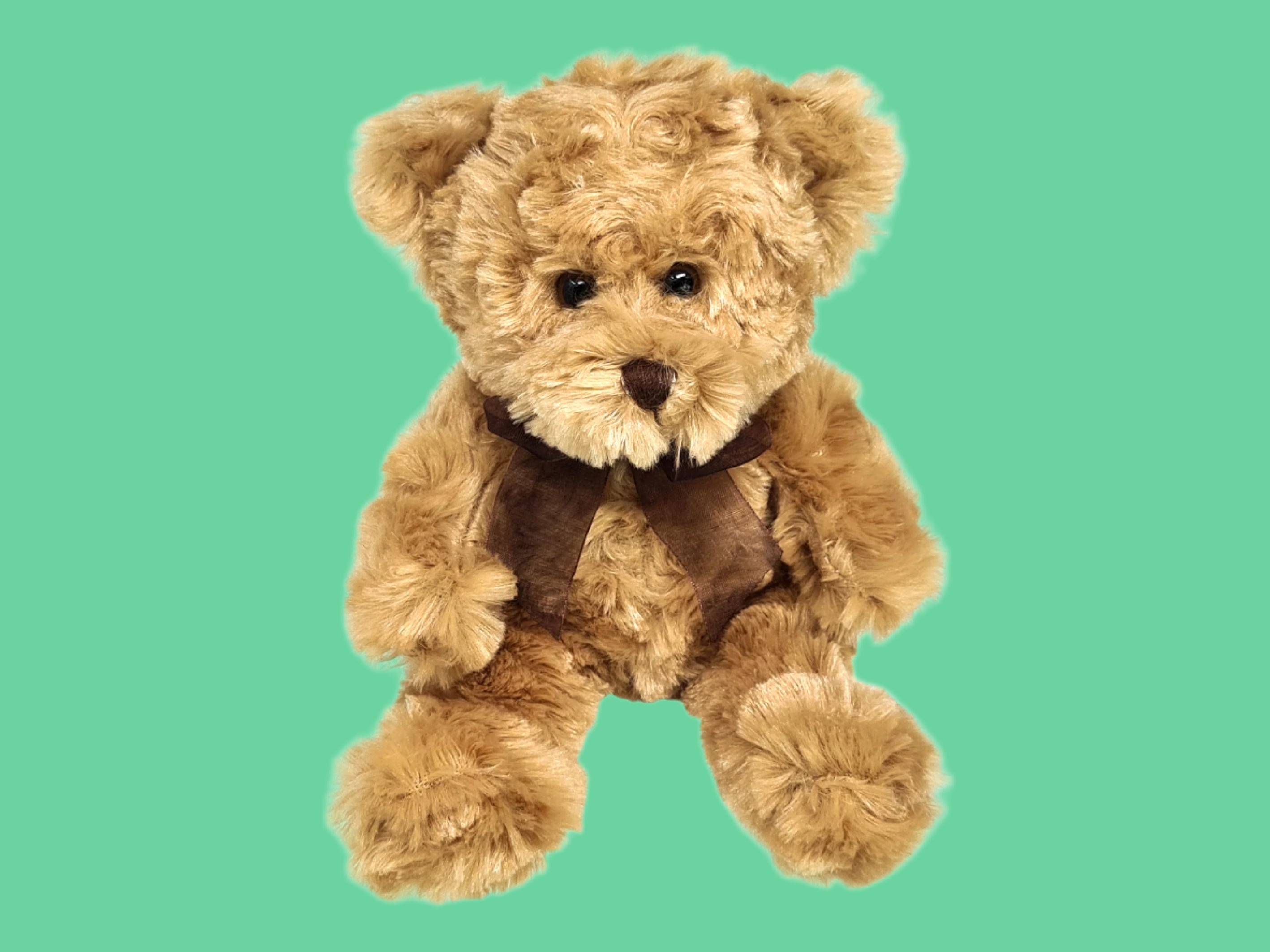 A small brown teddy bear with a bow around its neck.