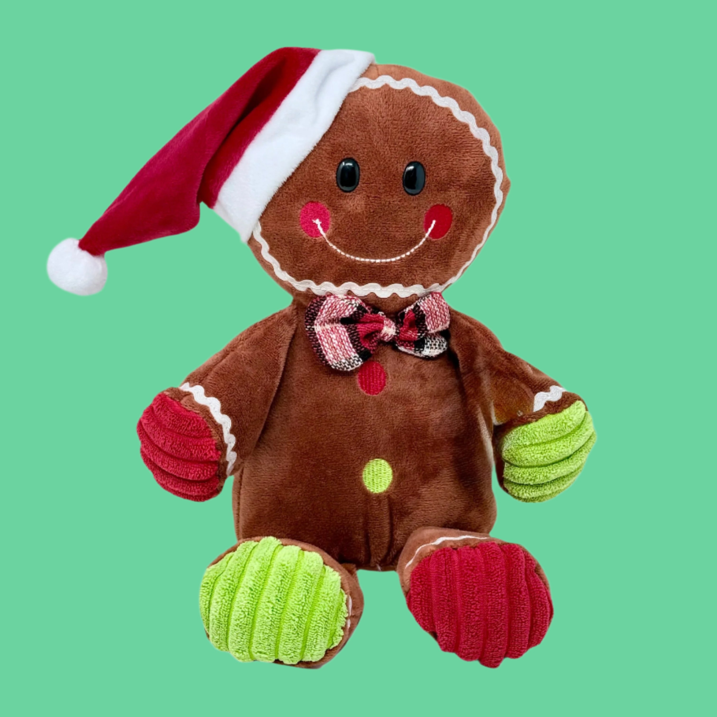 A plush toy resembling a gingerbread man with a red and green hat, brown 'ginger' body, and green 'icing' accents on the hands and a red scarf.