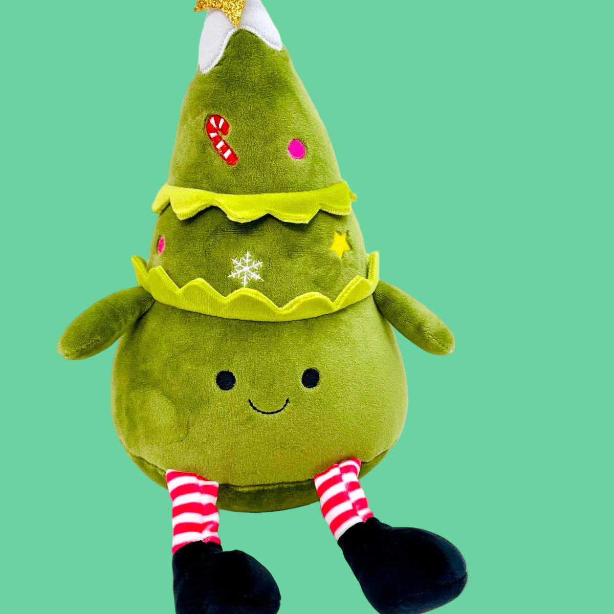 Green plush toy shaped like a Christmas tree with a star on a white background
