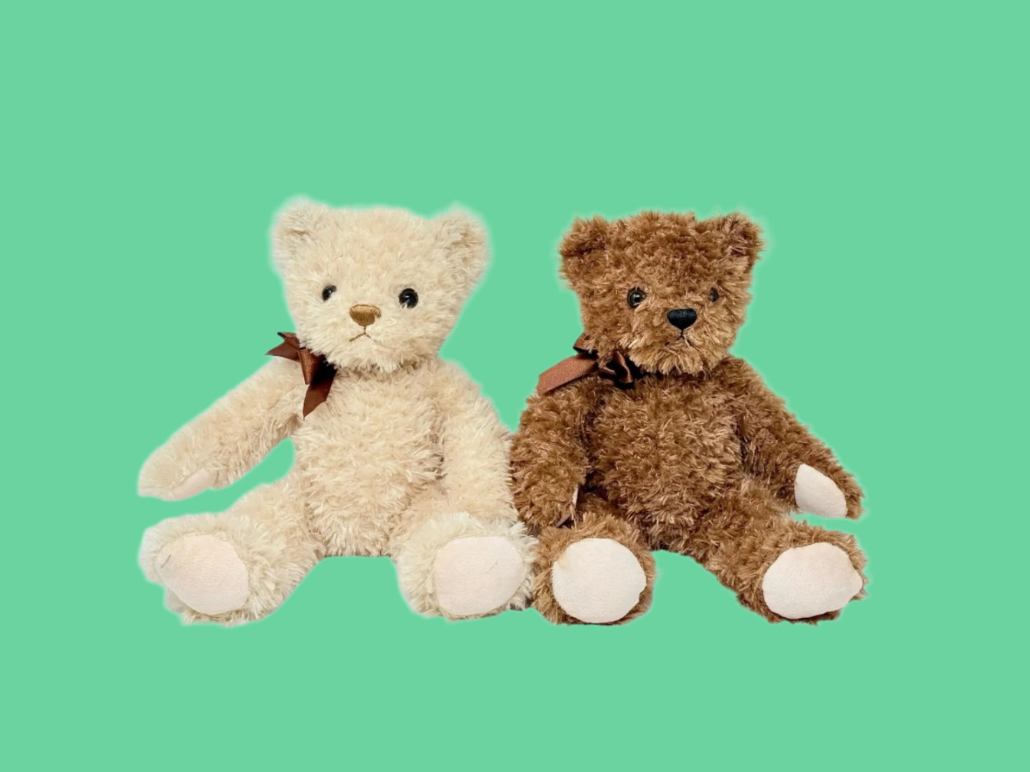 Two plush teddy bears, one light beige and one dark brown, sitting upright with bows around their necks.